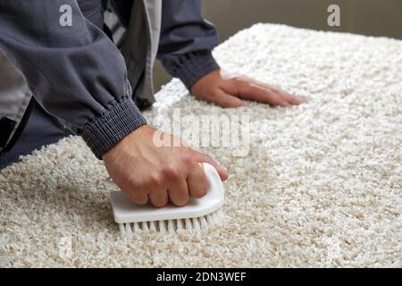 Homme tenant la brosse pour enlever la tache dans un service de nettoyage professionnel Banque D'Images