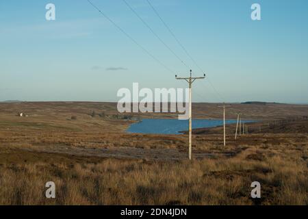 Image montrant des poteaux de télégraphe et des lignes téléphoniques s'étendant sur l'ouverture landes avec un petit réservoir à la distance Banque D'Images