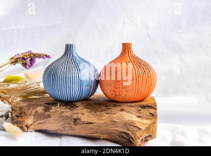 Deux beaux petits vases en céramique avec des bûches en bois sur fond blanc. Vaisselle en céramique, décoration. Banque D'Images