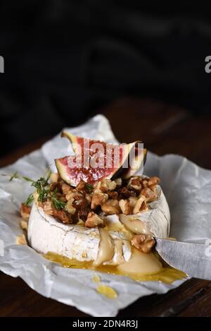 Camembert cuit avec des noix et du miel, des tranches de figues et de thym. Banque D'Images