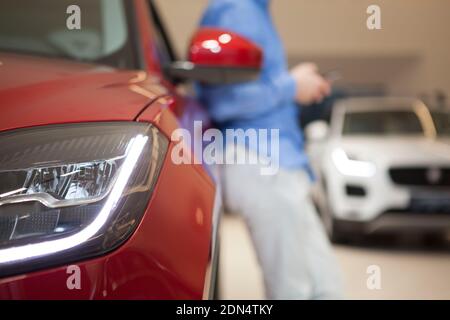 Gros plan court des feux de la voiture, homme méconnaissable s'inclinant sur la voiture sur un arrière-plan flou Banque D'Images