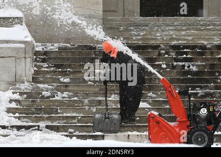 Un souffleur de neige passe devant un personnel du département des parcs de la ville de New York qui déblache les marches de la bibliothèque publique de la ville de New York après la première tempête d'hiver de la saison qui a laissé plus d'un pied de neige dans certaines parties de la ville, New York, NY, le 17 décembre 2020. Les Nor'easter ont laissé des parties du nord de l'État de New York couvertes de 40 pouces de neige, tandis que d'autres parties du nord-est ont vu moins de deux pieds mais ont laissé des routes glissantes et dangereuses pour les conducteurs, et ont arrêté le trafic aérien, y compris les expéditions prévues du vaccin Pfizer-BioNTech COVID-19. (Photo par Anthony Behar/Sipa USA) Banque D'Images