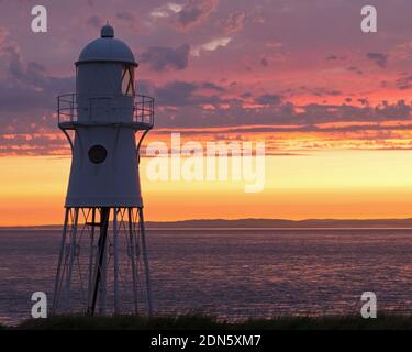 Une photo de coucher de soleil avec le phare de Black Nore surplombant le canal de Bristol sur la côte près de Portishead, Somerset, Angleterre, Royaume-Uni. Banque D'Images