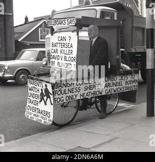 1960s, un militant historique, zélé et excentrique de la sécurité routière, l'ancien commandant de la marine Bill Boaks assis sur son célèbre vélo déocré avec des pancartes de protestation, à côté d'une route très fréquentée dans le sud de Londres, en Angleterre. ROYAUME-UNI. Le commandant Bill Boakes DSC héros naval et cycliste - une inspiration pour hurler Lord Sutch fondateur du parti officiel Monster Raving Loony - a tenu des élections parlementaires comme candidat pendant 30 ans tout d'abord sur un train, Bateaux et avions plate-forme et plus tard sur la sécurité routière campagne comme un monarchiste démocratique de sécurité publique blanc résident. Banque D'Images