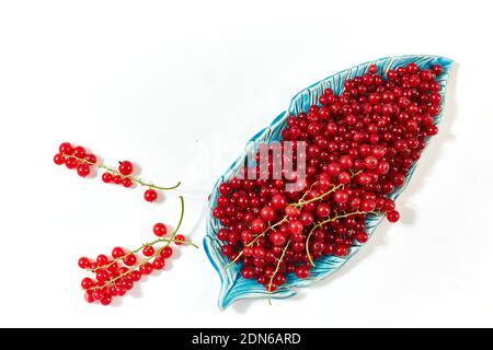 Fresh red currants in a handmade clay plate on a white table. View from above. Space for text. Stock Photo