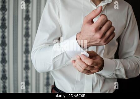 Le matin du marié. Le marié touche les boutons de manchette sur sa chemise Banque D'Images