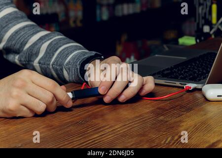 POD e-cigarette or nicotine vapor dispenser being charged in modern laptop with Pods Stock Photo