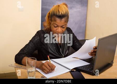 Belle fille assise à un bureau, tenant un crayon dans sa main et travaillant sur un dossier Banque D'Images