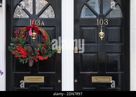 Couronne décorative de Noël sur une porte avant noire, Londres Angleterre Royaume-Uni Banque D'Images