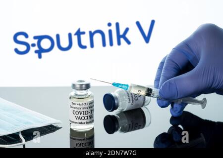 Morgantown, WV - 16 décembre 2020 : petite bouteille de vaccin contre le coronavirus avec seringue à l'arrière-plan du logo russe Spoutnik V. Banque D'Images