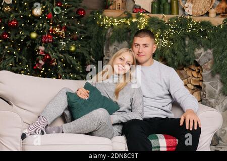 Adorable couple de mariage assis près de l'arbre de Noël et cheminée à la maison, le mari soin câlin belle femme enceinte, jeune famille profiter du bonheur, wint Banque D'Images