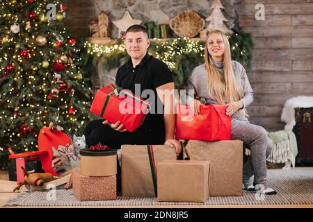 Adorable couple de mariage assis près de l'arbre de Noël et cheminée à la maison, le mari soin câlin belle femme enceinte, jeune famille profiter du bonheur, wint Banque D'Images