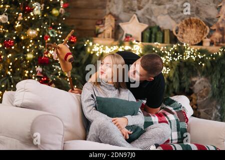 Adorable couple de mariage assis près de l'arbre de Noël et cheminée à la maison, le mari soin câlin belle femme enceinte, jeune famille profiter du bonheur, wint Banque D'Images