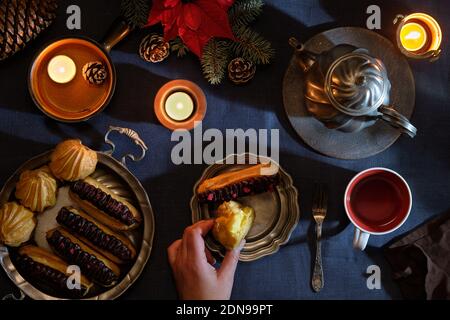 Exlaloires délicieuses ou pancakes et théière en étain et tasse de thé. Décoration de Noël naturelle, bougies, poinsettia rouge sur brindilles de sapin. Vue de dessus de Noël, plat Banque D'Images