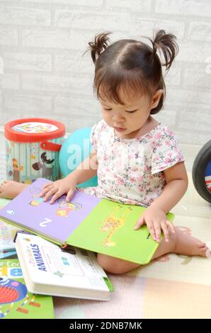 bébé fille de 2 ans tredller, palying avec des livres. Lecture d'un livre Banque D'Images