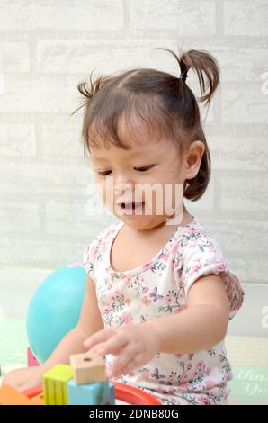 Petite fille, 2 ans, jouant de bloc de bois coloré Banque D'Images