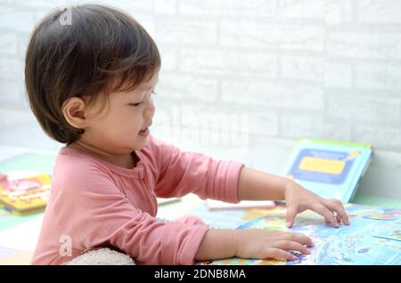 2 ans, todller, fille de bébé asiatique, jouant avec son livre.Reading un livre. Banque D'Images