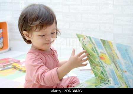 2 ans, todller, fille de bébé asiatique, jouant avec son livre.Reading un livre. Banque D'Images
