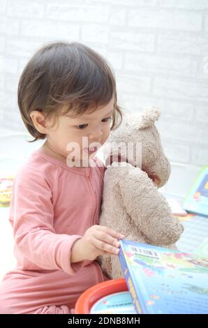 2 ans, todller, fille de bébé asiatique, jouant avec son livre.Reading un livre. Banque D'Images
