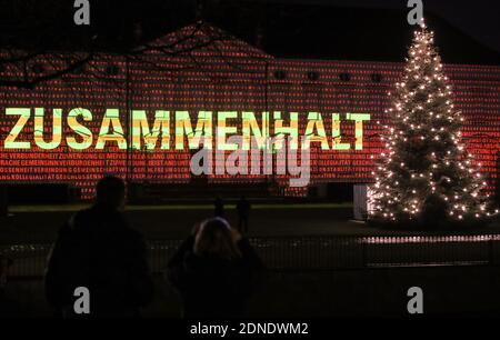 Berlin, Allemagne. 17 décembre 2020. Les visiteurs regardent le palais de Bellevue illuminé par la projection de la lumière du mot "se "ensemble" en allemand à Berlin, capitale de l'Allemagne, le 17 décembre 2020. Une projection de lumière sur le thème 'Lichtblick (Ray of Hope)' s'est tenue au Palais Bellevue à Berlin, dans le but de faire appel à la solidarité du public pour lutter contre la pandémie COVID-19. Credit: Shan Yuqi/Xinhua/Alay Live News Banque D'Images