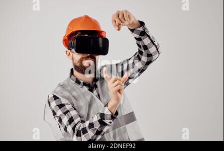Un constructeur dans un casque orange et des gestes de lunettes 3D Avec ses mains Copier l'arrière-plan de la lumière d'espace Banque D'Images