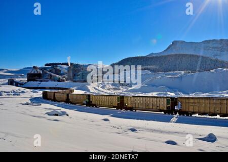 A winter landscape of a Canadian National Railway train loading coal ore from a coal processing plant in the foothills of the rocky mountains Stock Photo