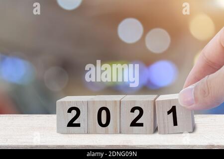 Hand holding wood cubes with numbers 2021 over blur bokeh background, Concept of beginning the new year Stock Photo