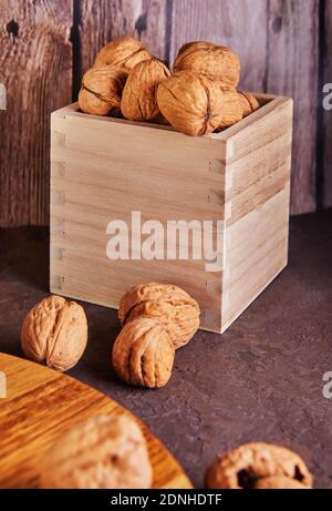 Noix dans une boîte en bois, entières et finement hachées, à côté de la garniture et des coquilles sur un fond en bois Banque D'Images