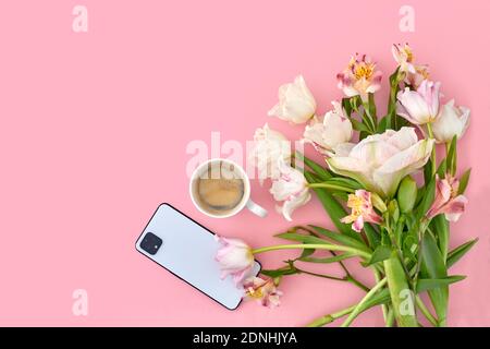 Tasse de café blanche avec tulipe et smartphone sur rose espace de copie en arrière-plan Banque D'Images