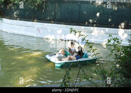 Jeune couple assis dans un vélo hydro et promenade sur le lac dans le parc Cismigiu. Banque D'Images