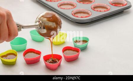 Chef pouring chocolate cake batter into  silicon heart-shaped mini molds. Chocolate cupcakes or chocolate muffins recipe, step by step preparation pro Stock Photo