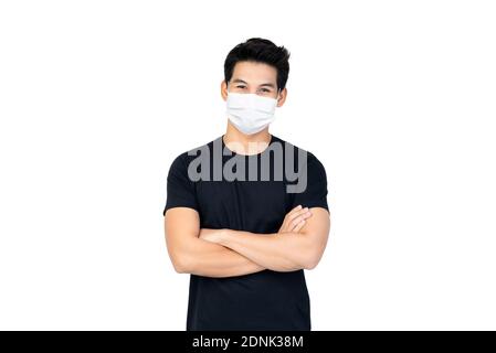 Homme asiatique en t-shirt noir avec les bras croisés face de port Masque à protéger de COVID-19 sur fond blanc isolé Banque D'Images