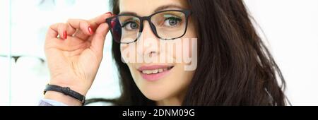 Portrait d'une femme souriante en lunettes sur fond de vitrine avec optique. Banque D'Images