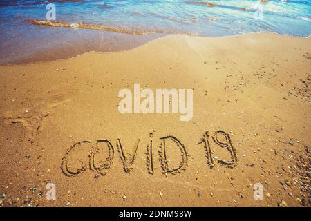 Inscription Covid 19 sur le sable de la plage déserte. Concept de pandémie Banque D'Images