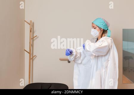 La jeune fille d'un professionnel de la santé est vêtue d'un uniforme de protection, d'un capuchon chirurgical, de gants en latex et d'un masque Banque D'Images