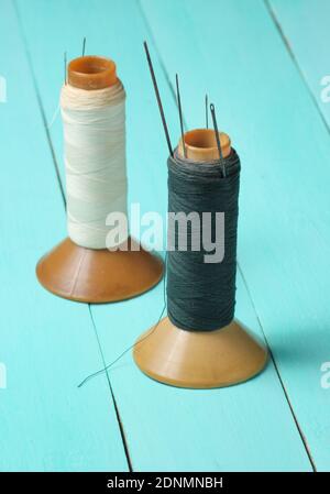 Bobines de fil vintage avec aiguilles sur une table en bois bleu Banque D'Images