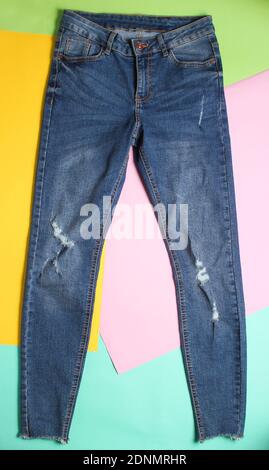 Female fashionable ragged faded jeans on a colored pastel background. Minimalism, top view Stock Photo