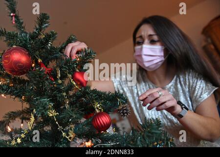 Munich, Allemagne. 17 décembre 2020. Sujet photo Lonely Weihafterten 2020 dans la pandémie du coronavirus: Une jeune femme avec un masque facial, le masque décore son Weihaftertsbaum. Pandémie, verrouillage, shutdown, valeur de l'incidence. MODÈLE DISPONIBLE ! | utilisation dans le monde crédit: dpa/Alay Live News Banque D'Images