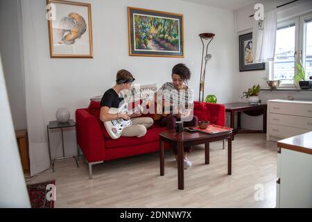 Les jeunes jouent à la guitare sur le canapé Banque D'Images
