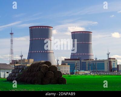 Centrale nucléaire biélorusse. Champ vert et botte de foin sur le fond de la centrale nucléaire Banque D'Images