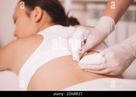 Photo rognée d'un cosmetologue professionnel qui retire les têtes noires sur le dos d'une femme. Esthéticienne nettoyant les pores sur le corps d'une cliente Banque D'Images