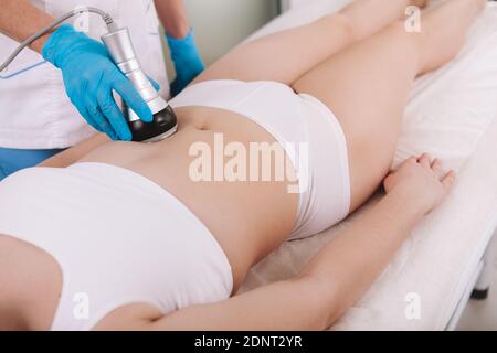 Femme méconnaissable recevant un traitement de levage rf sur son ventre à la cosmétologie clinique Banque D'Images
