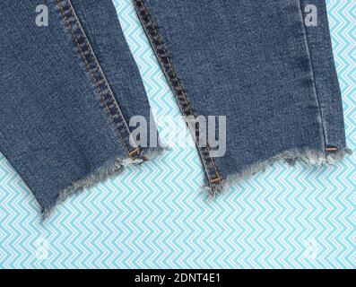 Jeans déchiquetés sur fond bleu créatif. Vue de dessus. Banque D'Images