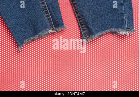 Jeans déchiquetés sur fond rouge créatif pois. Vue de dessus. Banque D'Images