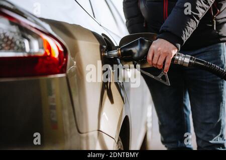 Homme ravitaillant sa voiture dans la station-service ou de remplissage par le naphta ou le carburant, processus de ravitaillement Banque D'Images