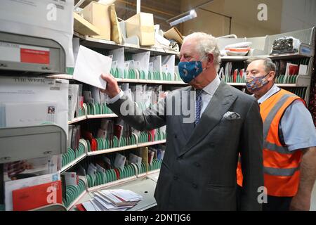 The Prince of Wales helps to sort letters with Royal Mail employee Mark Messer during a visit to Royal Mail's Delivery Office, in Cirencester, to recognise the vital public services that the country's postal workers provide, especially this year and in the run-up to Christmas. Stock Photo