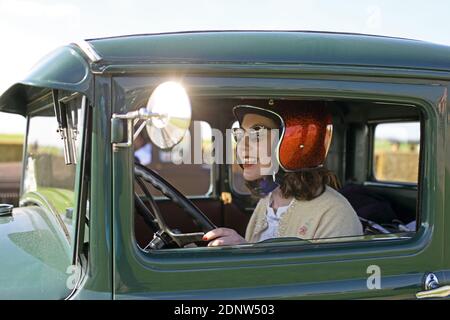 Souriante fille attrayante avec casque assis dans une voiture vintage Banque D'Images