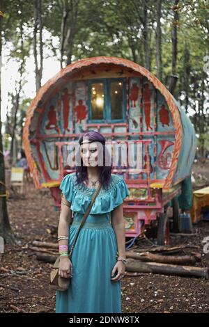 Jeune fille hippie bohème posant devant une caravane tzigane en forêt. Banque D'Images