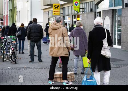 Dortmund, Allemagne, 18 décembre 2020: Les clients attendent sur le trottoir devant une succursale de Deutsche Post / DHL à Dortmund. En raison des restrictions du deuxième verrouillage de la pandémie de corona, seuls 3 clients sont autorisés à rester dans cette succursale en même temps. Banque D'Images