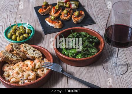 vue horizontale en gros plan d'une casserole avec crevettes frites ail et persil, ainsi que d'autres plats et tasses de tapas espagnols du vin du mercredi Banque D'Images